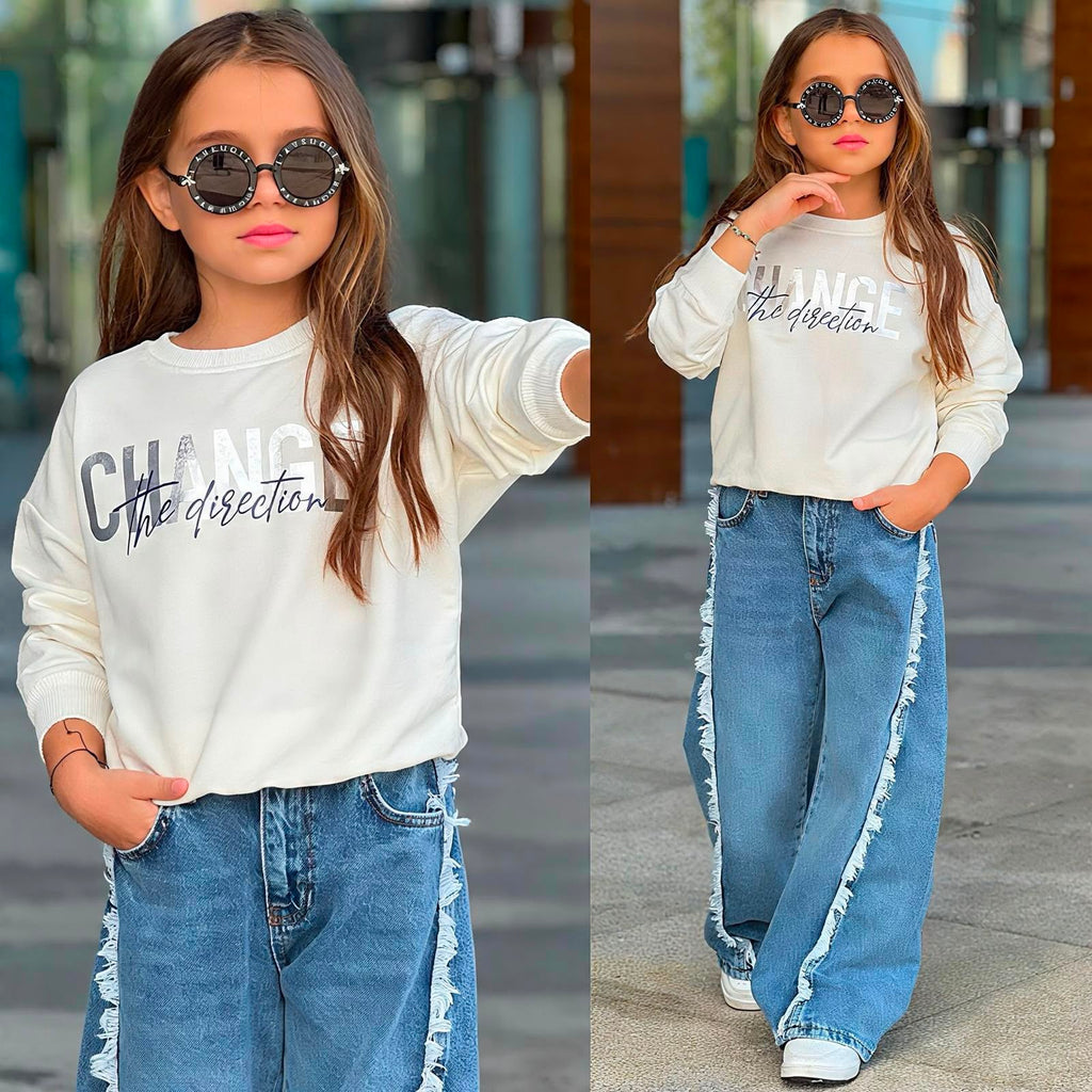 Mädchen-Set „Change the Direction" – Detailansicht Sweater-Print und Ganzansicht mit blauer Baggy-Jeans und Fransen-Seitennaht