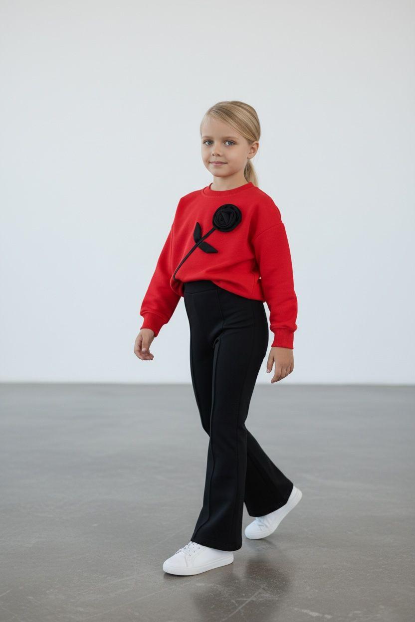 Mädchen in rotem Sweater mit schwarzer 3D-Rose und schwarzer Schlaghose