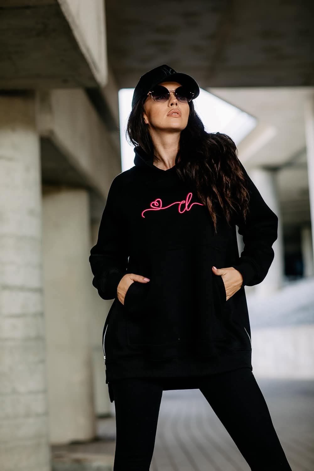 COTTONLAND Oversize-Hoodie in Schwarz, Vorderansicht mit Händen in der Kängurutasche und sichtbaren seitlichen Zips