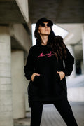 COTTONLAND Oversize-Hoodie in Schwarz, Vorderansicht mit Händen in der Kängurutasche und sichtbaren seitlichen Zips
