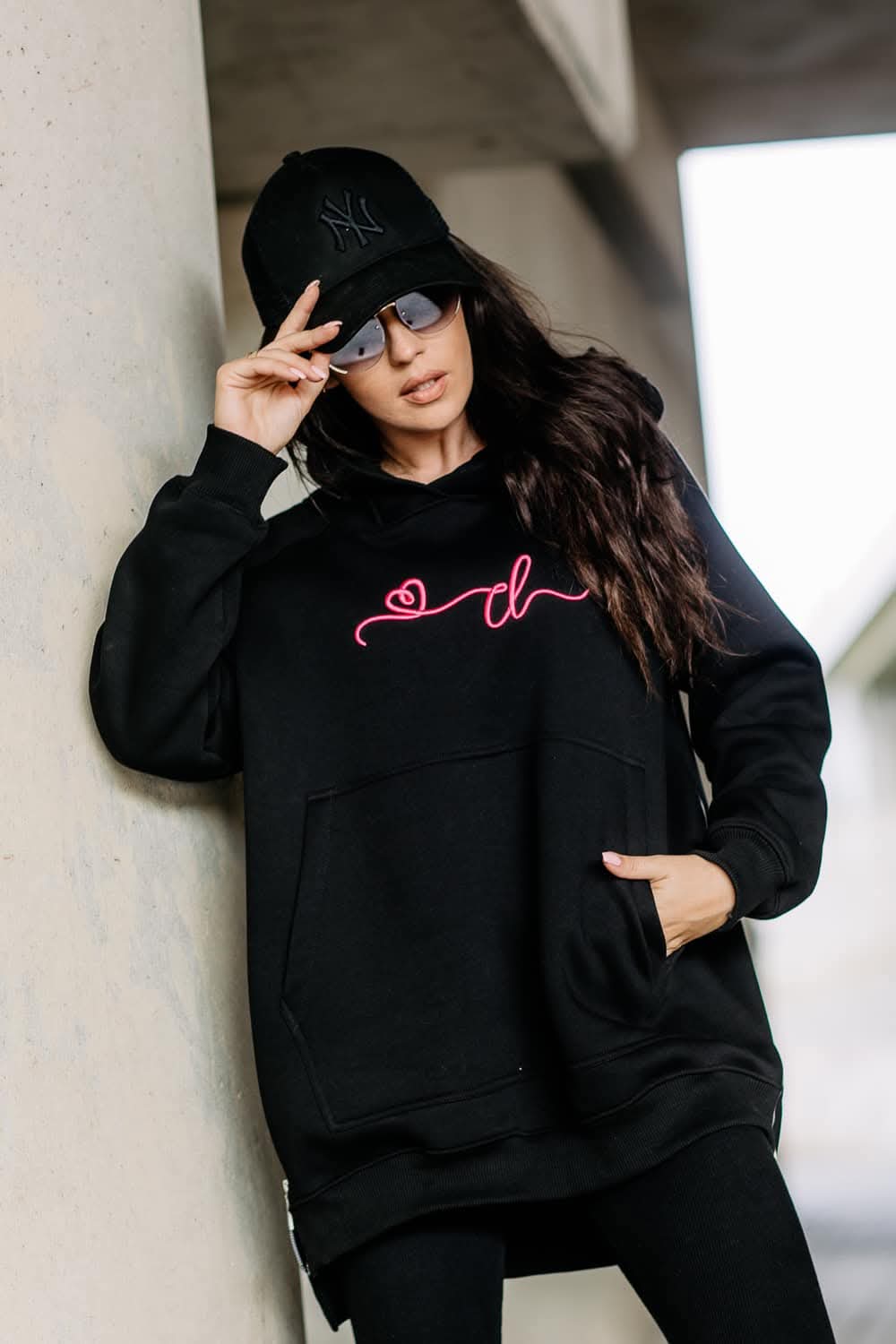 Schwarzer COTTONLAND Damen-Hoodie mit pinker Brustverzierung und großer Kängurutasche am Model