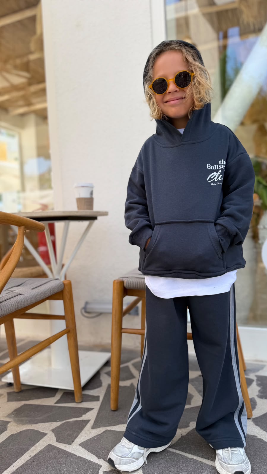 Kind trägt das Bullseye Club Streetwear Set in Anthrazit, Oversize-Hoodie mit Frontprint und weite Hose, Vorderansicht
