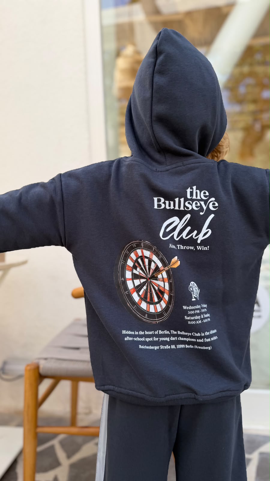 Rückenprint des Bullseye Club Hoodies mit Dartscheibe und Aufschrift The Bullseye Club, Aim Throw Win