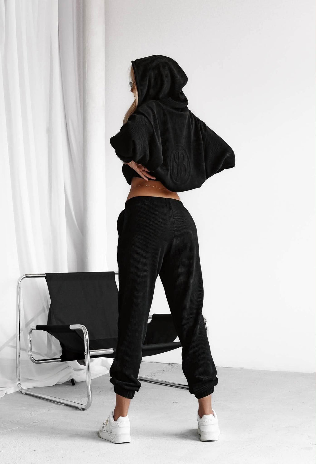 Rückansicht des schwarzen Ripp-Sets: Kapuzenjacke und Hose mit Bündchen am Bein
