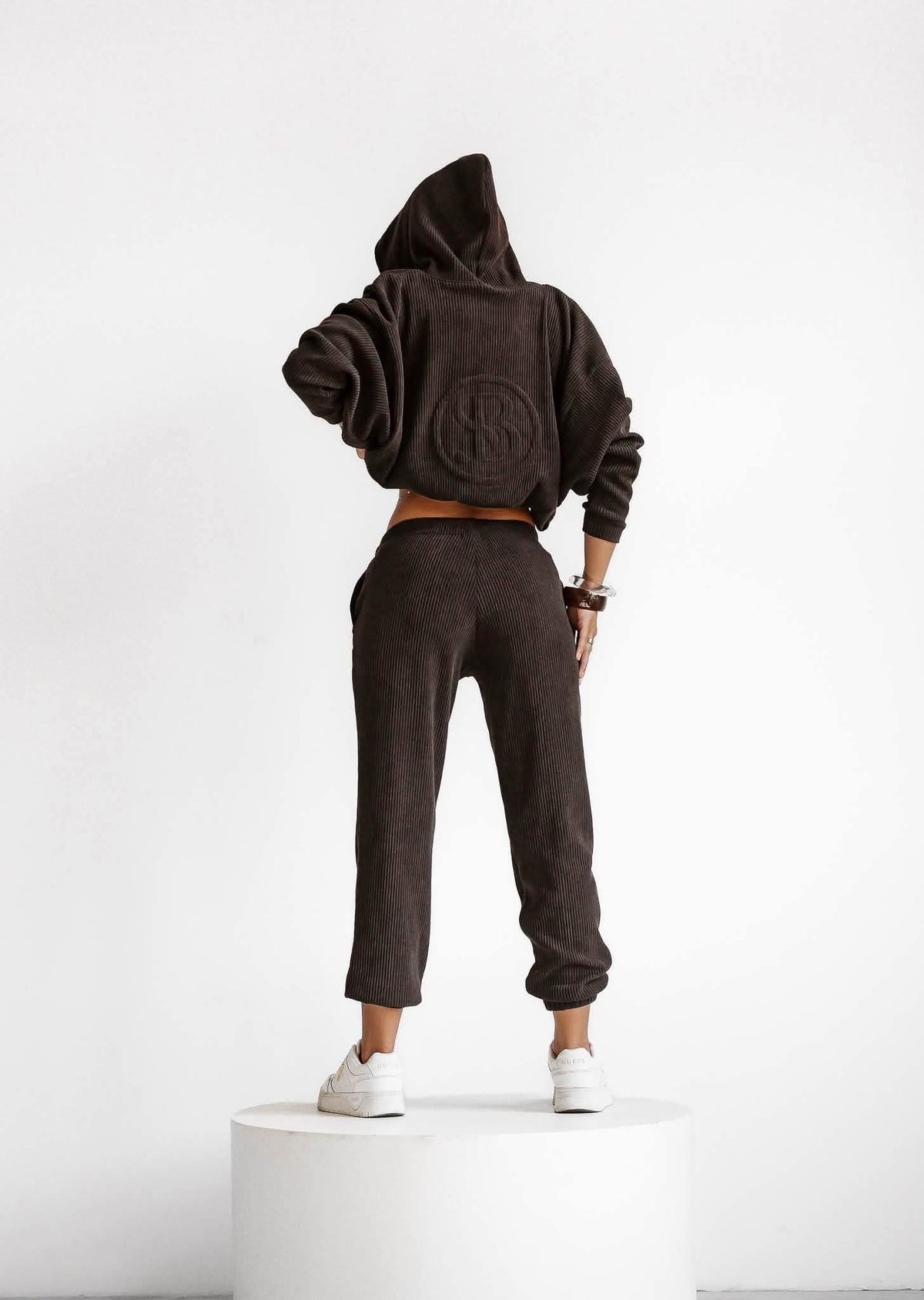 Rückansicht des schokoladebraunen Ripp-Sets: Kapuzenjacke mit Rückentasche und bequemer Hose