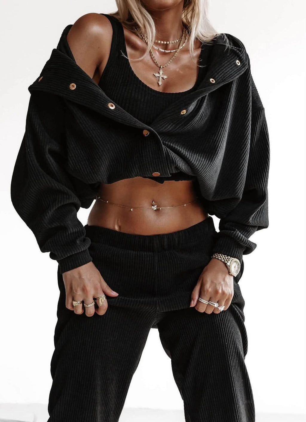 Schwarzes 3-teiliges Ripp-Set: Jacke mit Druckknöpfen offen über die Schulter gelegt, Crop-Top und Hose