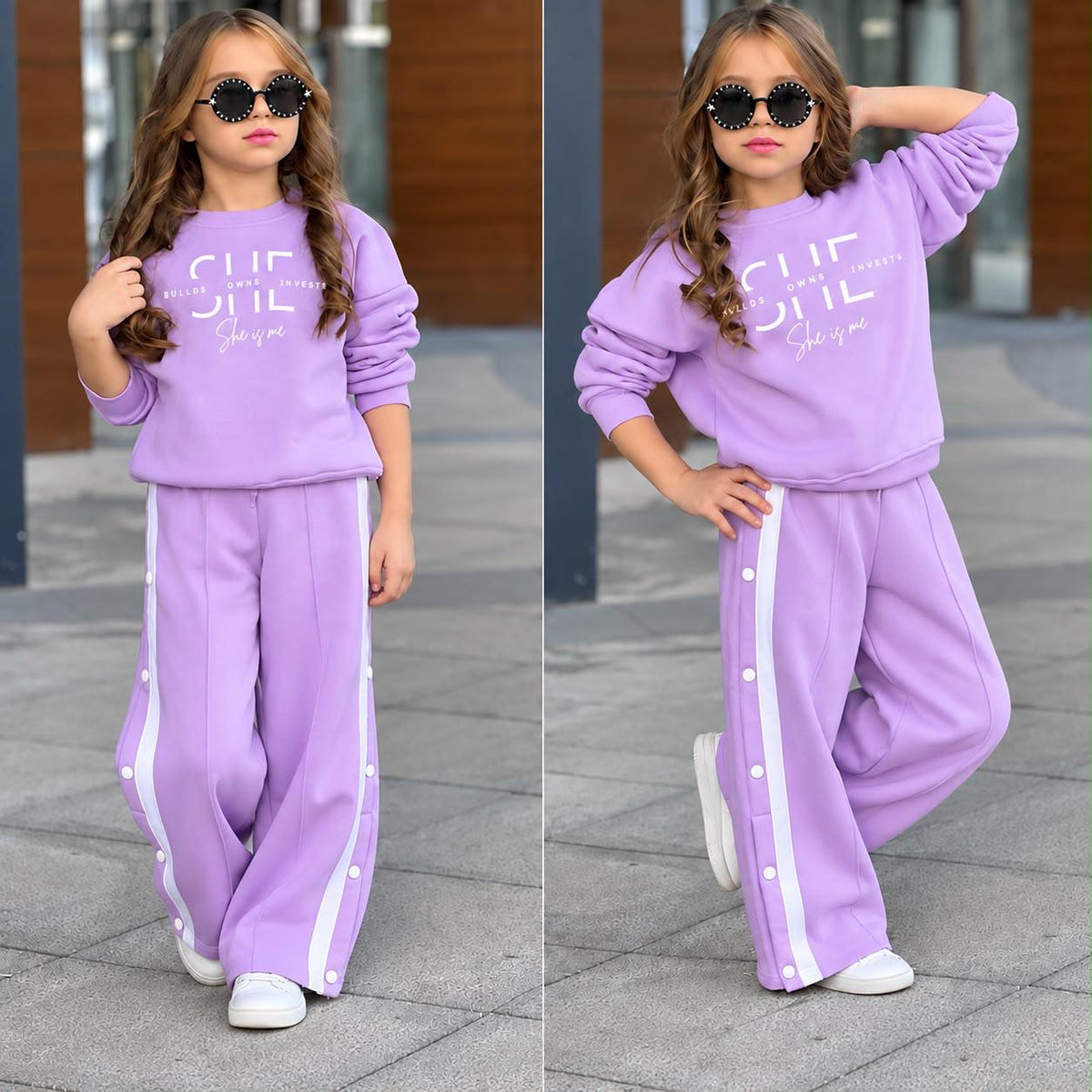 Mädchen im lilafarbenen Sweatset „She Is Me“ mit Rundhals-Sweatshirt und Wide-Leg-Hose mit weißen Seitenstreifen und Knöpfen.
