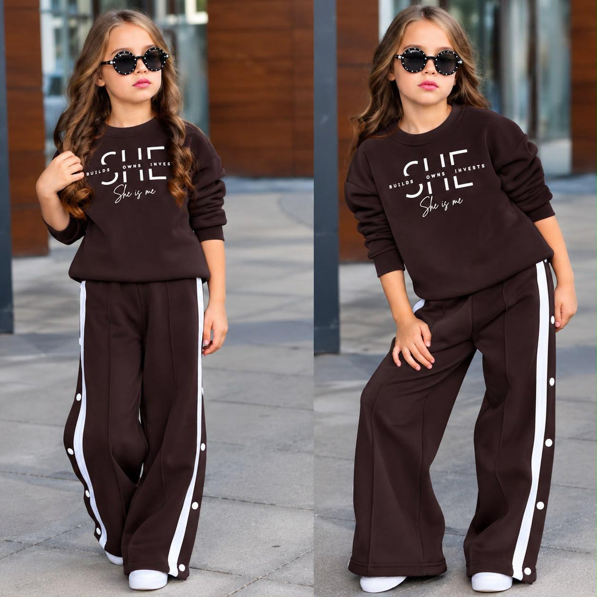 Mädchen im dunkelbraunen Sweatset „She Is Me“ mit weitem Bein, weißen Seitenstreifen und dekorativen Knöpfen.