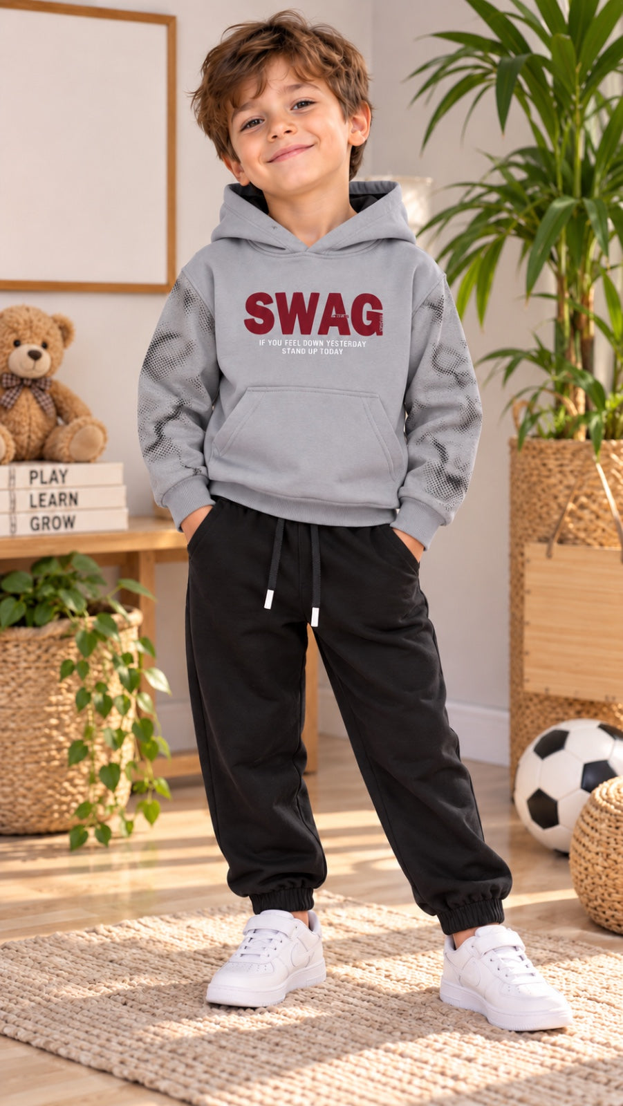 Junge im zweiteiligen SWAG-Set mit grauem Hoodie, gemusterten Ärmeln und schwarzer Jogginghose mit Kordelzug