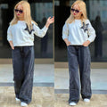 Mädchen trägt das Star Style Set mit cremefarbenem Sweatshirt und dunkelgrauer Wide-Leg-Jeans mit dekorativen Stern-Applikationen