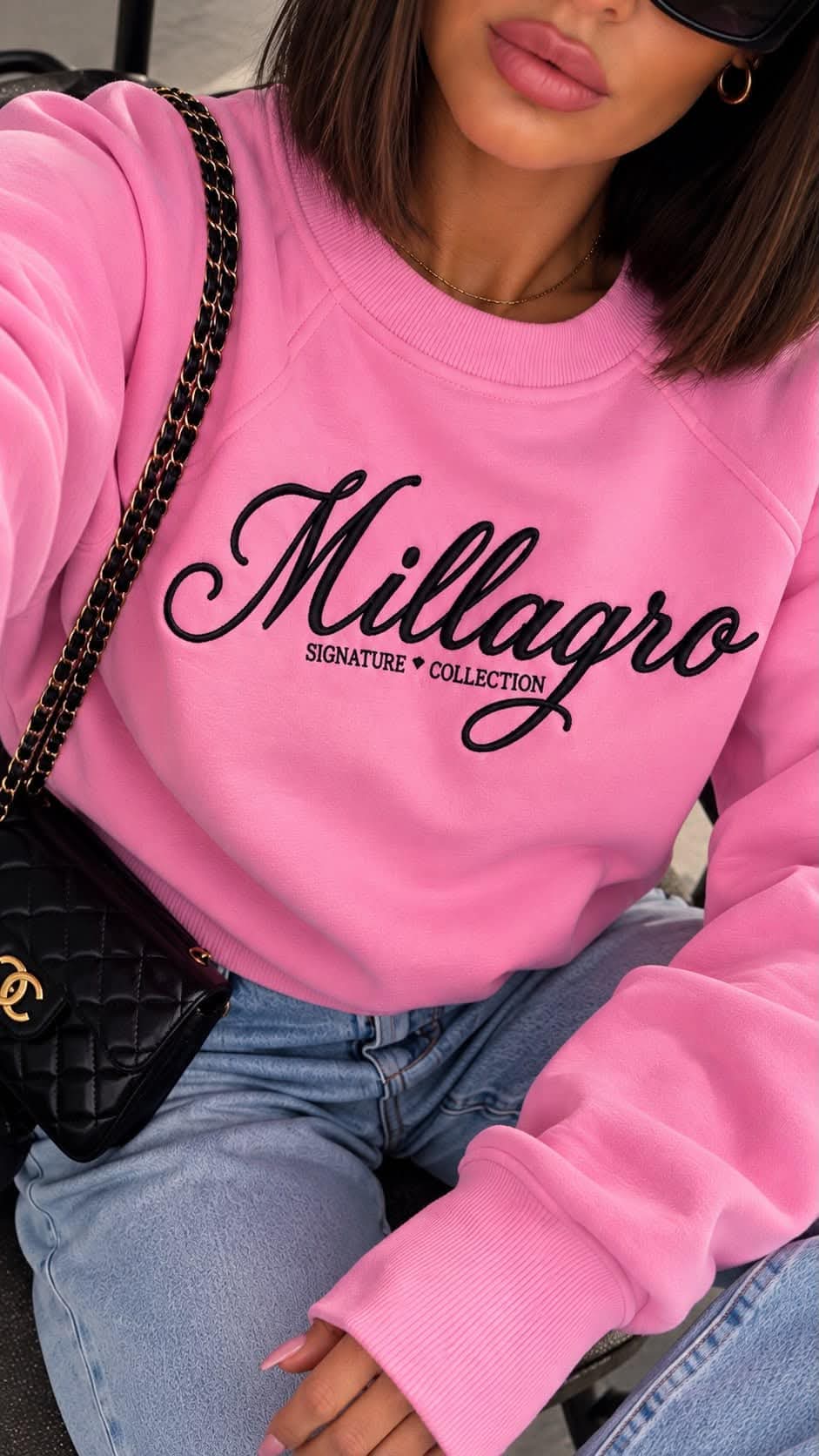 MILLAGRO Damen-Sweatshirt in Rosa mit schwarzem Signature-Collection-Schriftzug, getragen mit heller Jeans.