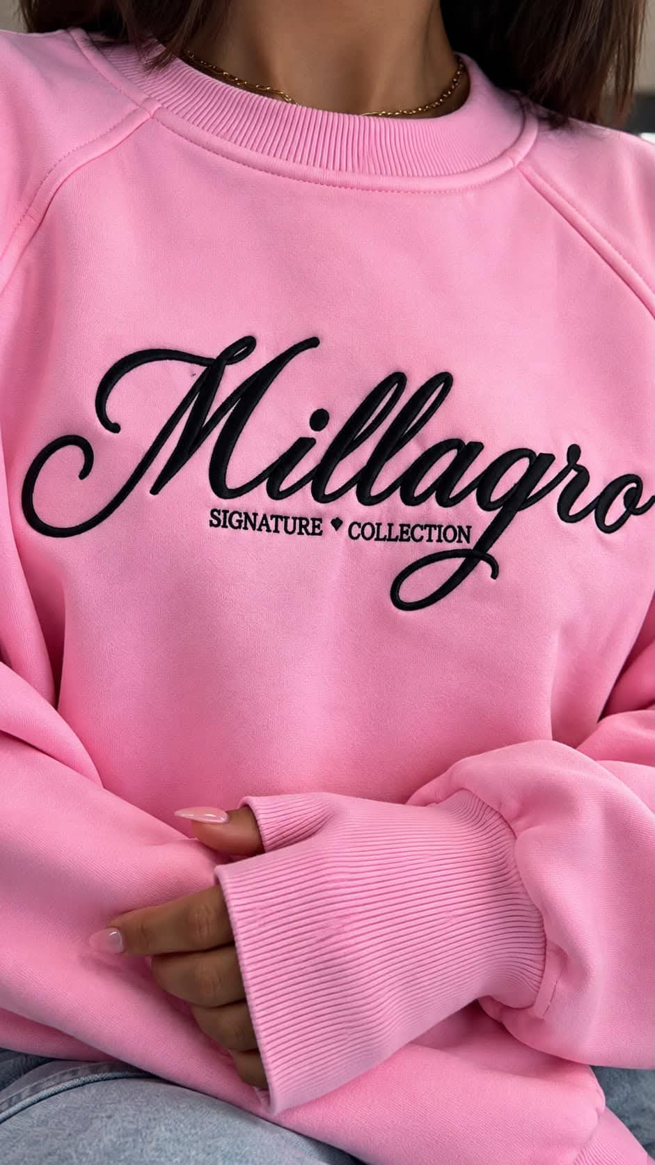 Nahaufnahme des MILLAGRO Damen-Sweatshirts in Rosa mit schwarzer Logo-Stickerei und geripptem Rundhalsausschnitt.