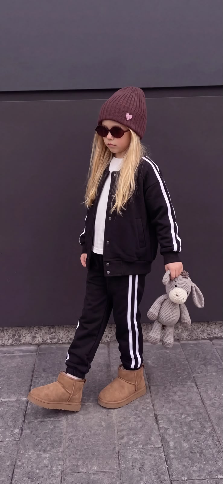 Mädchen im schwarzen dreiteiligen College-Set mit Druckknopfjacke, Jogginghose mit weißen Seitenstreifen und weißem T-Shirt