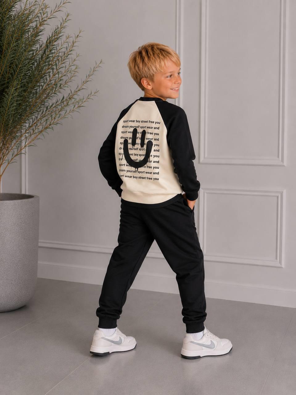 Schwarz-cremefarbenes Jungen-Sweatset Happy Street von hinten mit großem schwarzem Smiley und Schriftzügen.