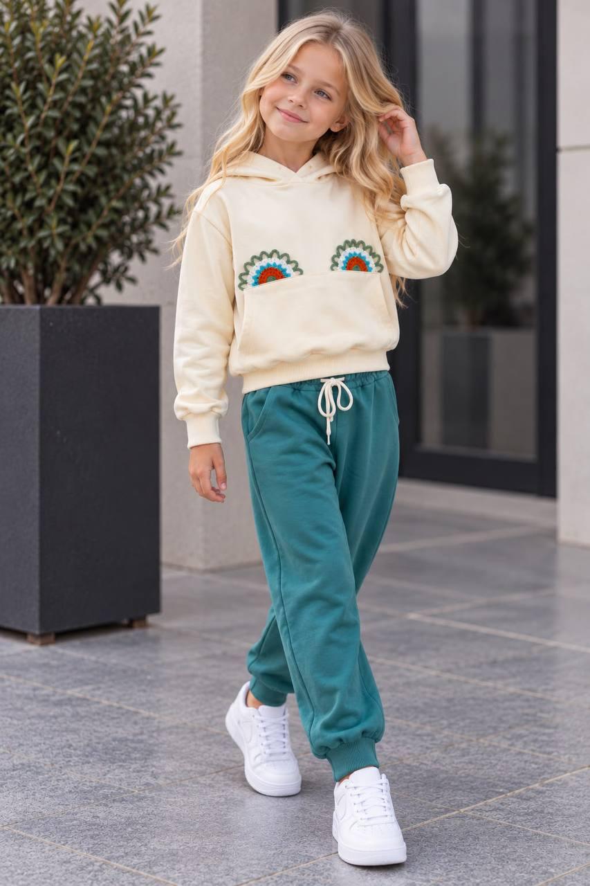 Rainbow Love Mädchen-Set mit cremefarbenem Hoodie, Kängurutasche und petrolgrüner Hose mit weißem Kordelzug.