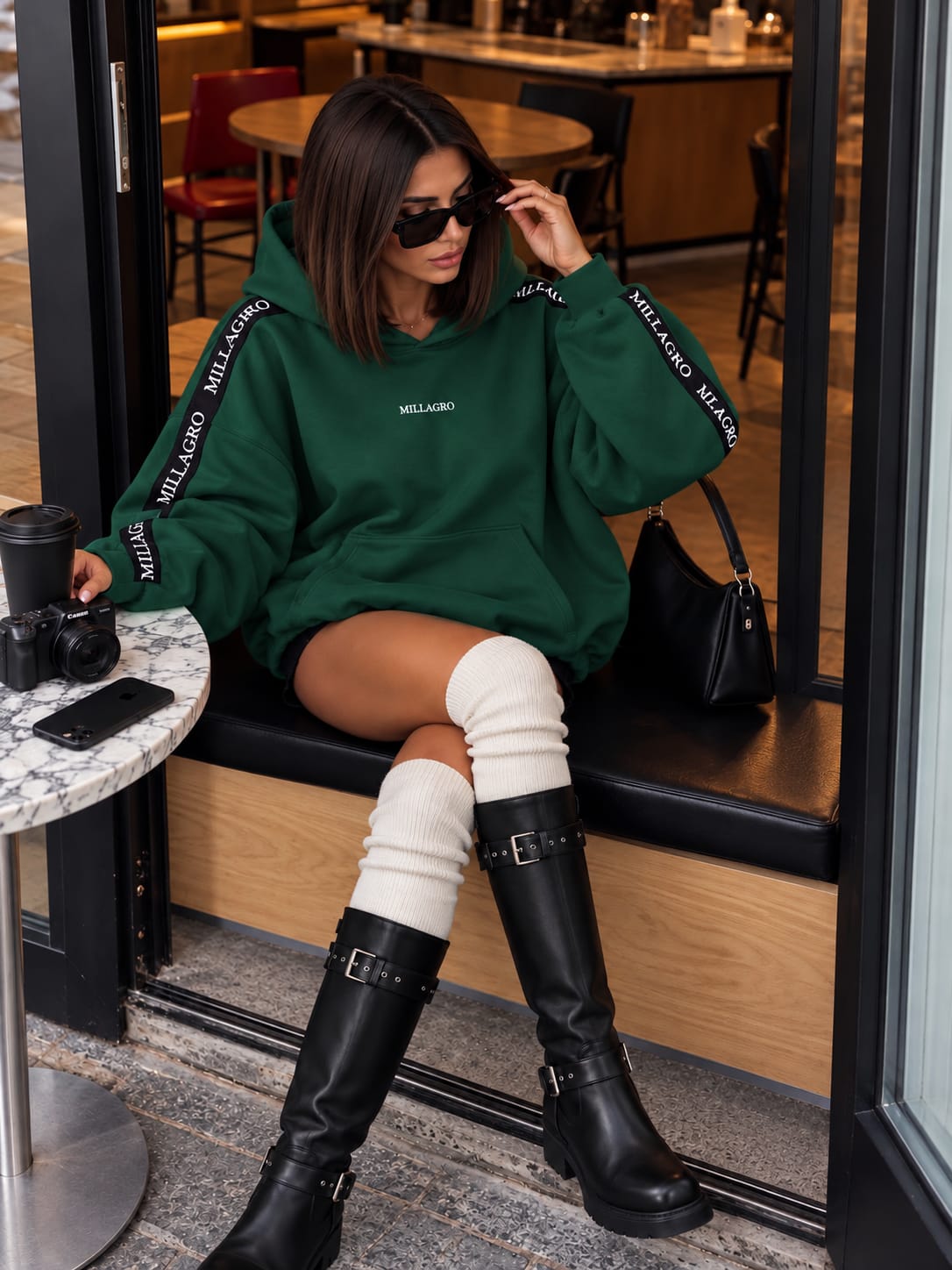 Oversize Hoodie Millagro in Dunkelgrün mit schwarzen Logo-Bändern und hohen schwarzen Boots