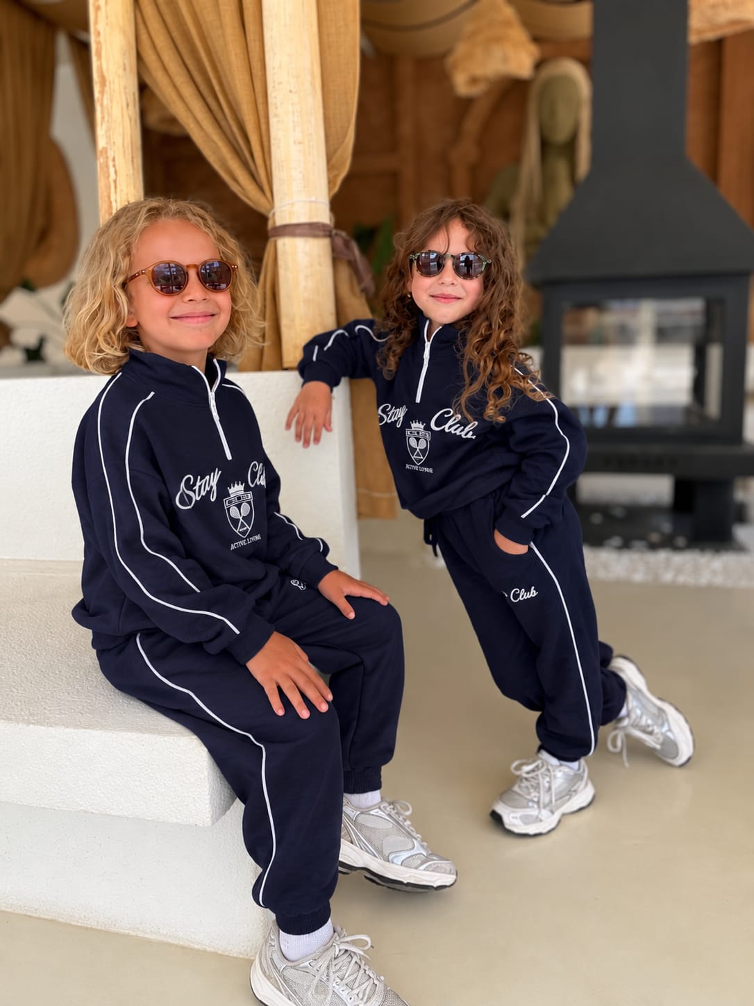 Stay Club Kids Set: schwarzes 2-teiliges Set mit dunkelgrünen Paspeln, von zwei Kindern mit Sneakern