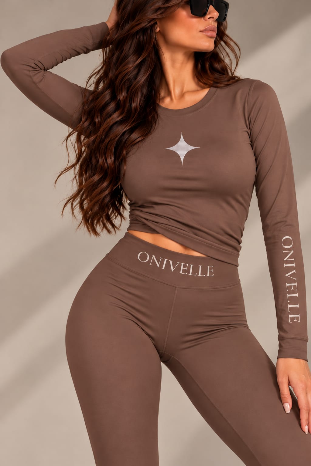 ONIVELLE Damen-Langarmshirt in Braun mit Sternmotiv und Schriftzug am Ärmel, am Model mit passender Leggings kombiniert.