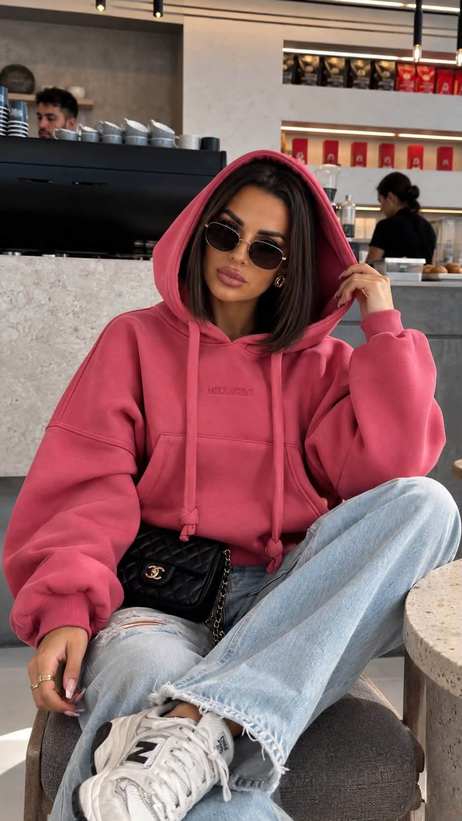MILLAGRO MONROU Oversize-Hoodie in Himbeerrosa mit aufgesetzter Kapuze, kombiniert mit Jeans und Sneakern.