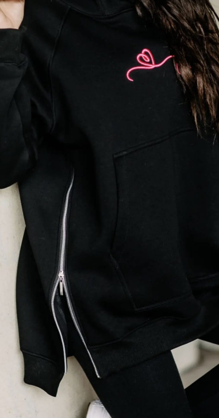 Detail des geöffneten seitlichen Reißverschlusses am schwarzen COTTONLAND Hoodie mit abgestuftem Saum