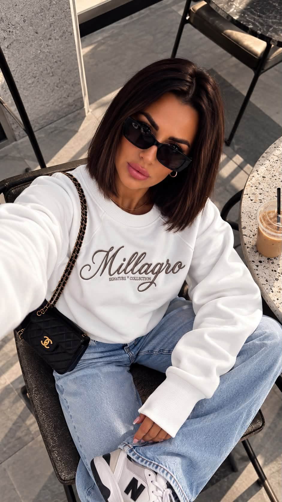 MILLAGRO Damen-Sweatshirt in Weiß mit dunkler Logo-Stickerei und langen Rippbündchen, von oben gezeigt.