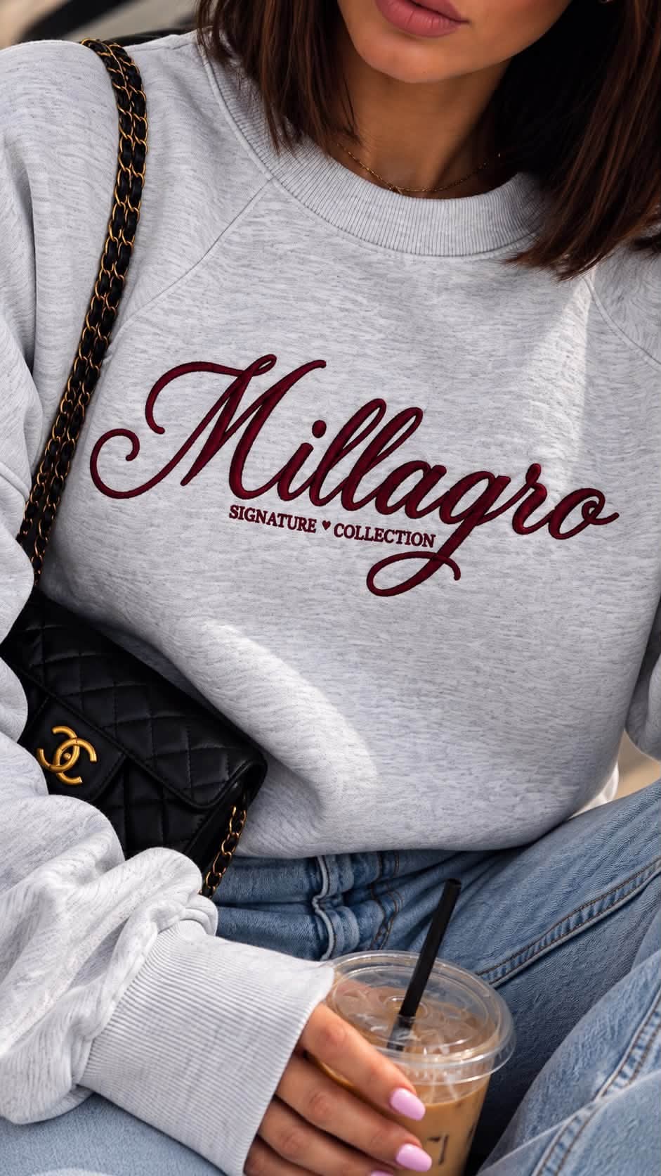 Nahaufnahme des hellgrau melierten MILLAGRO Sweatshirts mit bordeauxfarbener Logo-Stickerei und langen Rippbündchen.
